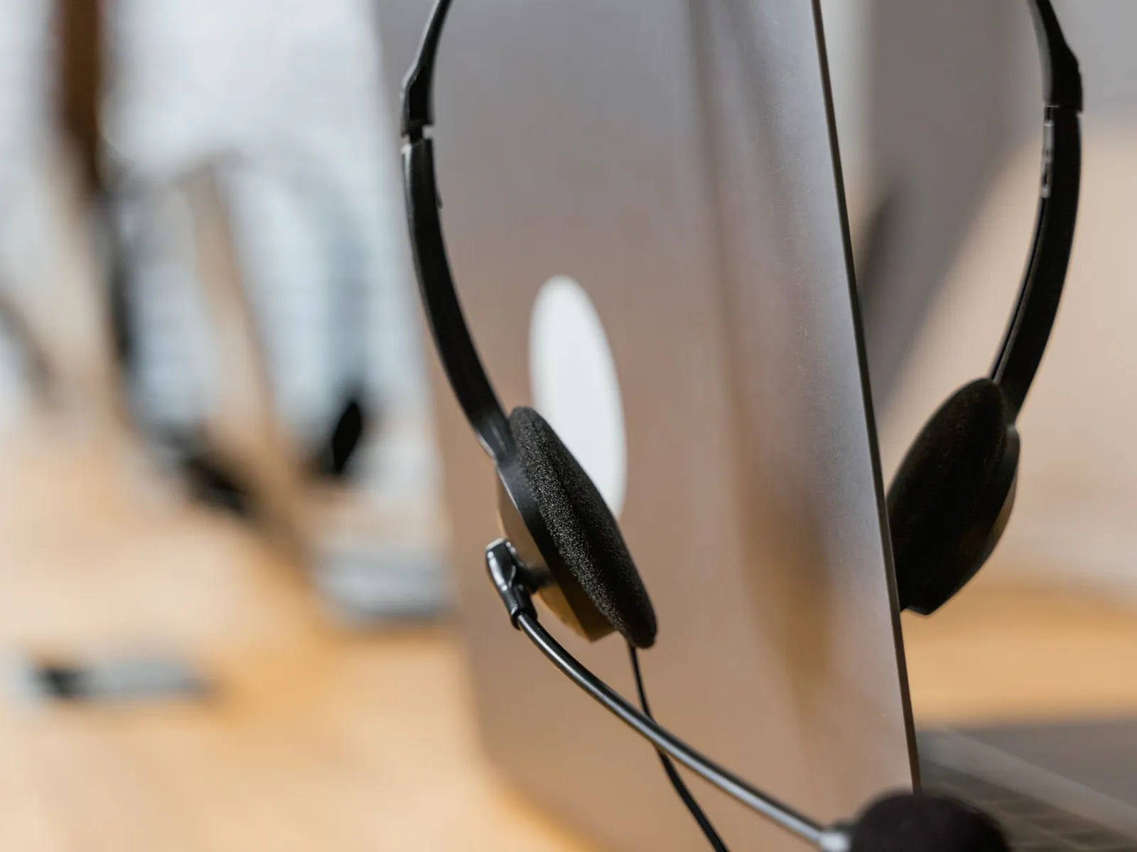 Ein Headset hängt an einem aufgeklappten Laptop in einem hellen Büro.