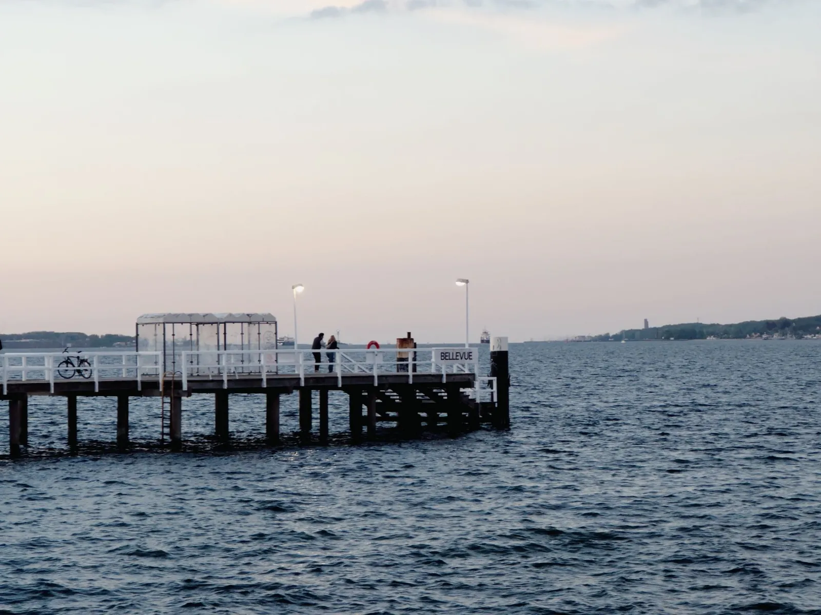 Anleger an der Kieler Förde im Abendlicht, dahinter das Wasser bis zum anderen Ufer.